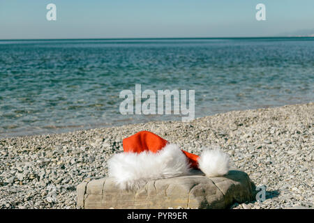 Santa Claus hat lies on a large stone on the seashore Stock Photo