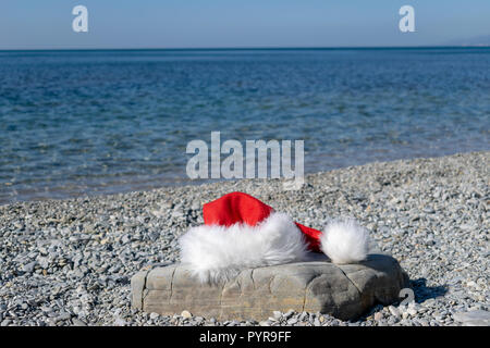 Santa Claus hat lies on a large stone on the seashore Stock Photo