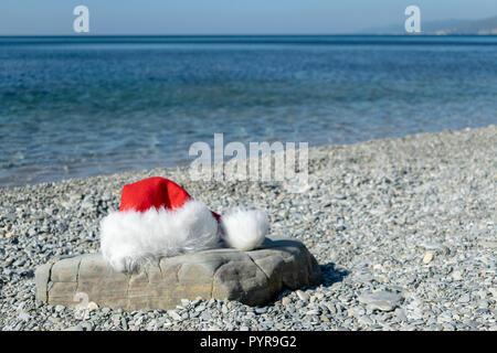 Santa Claus hat lies on a large stone on the seashore Stock Photo