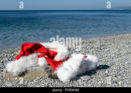 Santa Claus clothing and hat lies on a large stone on the seashore Stock Photo