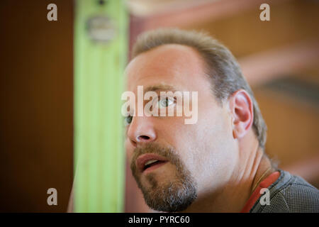 Male builder looking at a measuring tape. Stock Photo