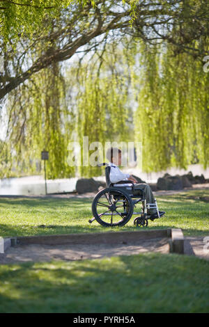 Boy in wheelchair in park Stock Photo