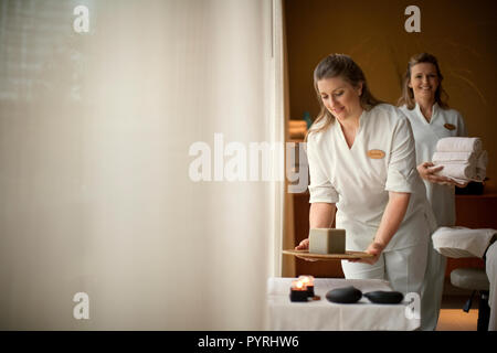 Two smiling middle-aged massage therapists at a health spa arranging and preparing the room for their next client. Stock Photo