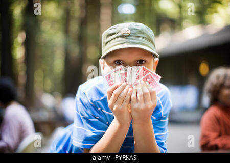 Portrait of a boy holding playing cards.