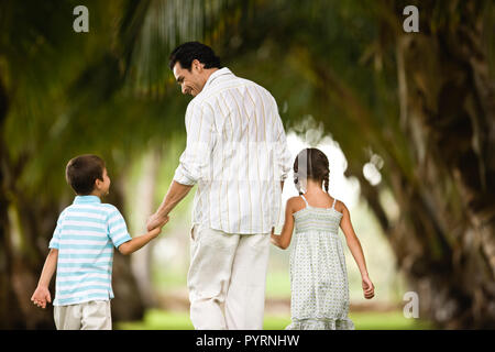 Rear view of father and children walking hand in hand. Stock Photo