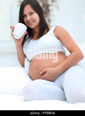 happy pregnant woman drinking milk sitting in the living room. Stock Photo