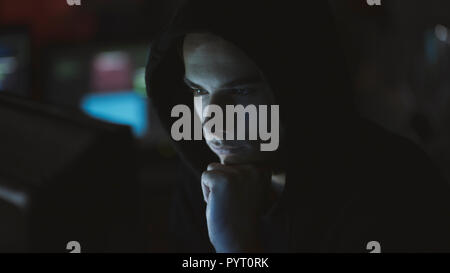 Young professional hacker working in a dark office with computers, cyber security and hacking concept Stock Photo