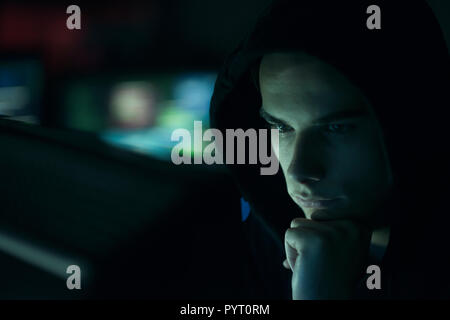 Young professional hacker working in a dark office with computers, cyber security and hacking concept Stock Photo