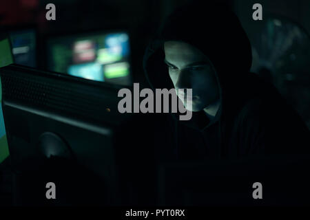 Young professional hacker working in a dark office with computers, cyber security and hacking concept Stock Photo