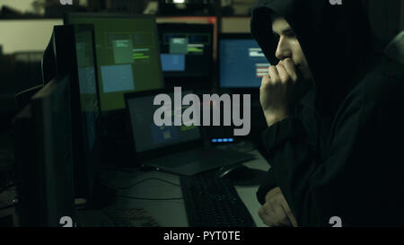 Young professional hacker working in a dark office with computers, cyber security and hacking concept Stock Photo
