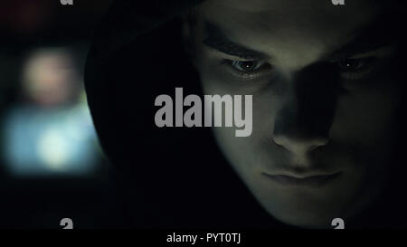 Cool young hacker with hoodie posing in the dark, cyber security and coding concept Stock Photo