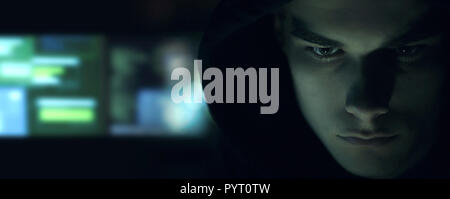 Cool young hacker with hoodie posing in the dark, cyber security and coding concept Stock Photo