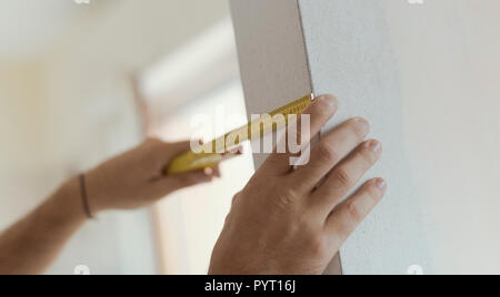 Man measuring a wall using a folding ruler: home renovation and construction concept Stock Photo