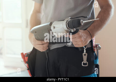 Professional repairman working with a drill and renovating an apartment, home makeover concept Stock Photo
