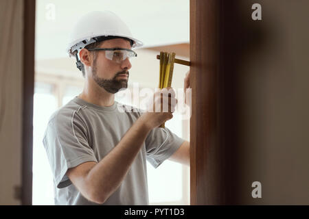 Carpenter taking measures with a folding ruler: home renovation and construction concept Stock Photo
