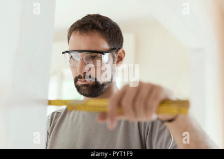 Man measuring a wall using a folding ruler: home renovation and construction concept Stock Photo