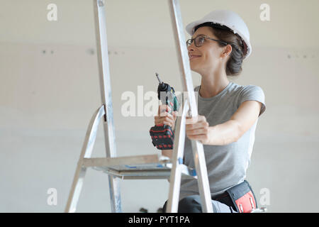 Young smiling woman using a drill, home renovation and DIY concept Stock Photo