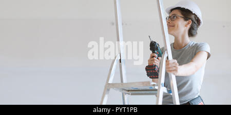 Young smiling woman using a drill, home renovation and DIY concept Stock Photo