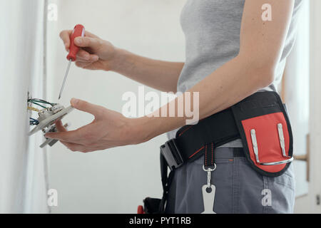Professional female electrician fixing a socket at home using a screwdriver, home renovation concept Stock Photo