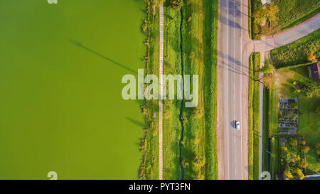 Aerial view from Drone: Road with a car along below green lake. Stock Photo