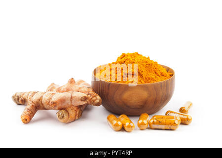 Turmeric capsules and turmeric powder in wooden bowl on white background. Herbal Stock Photo