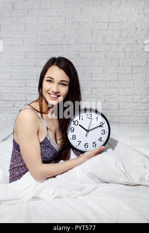 Happy woman waking up and turning off the alarm clock Stock Photo