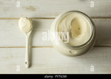 Mayonnaise in a glass jar with a spoon on white wooden boards. Stock Photo