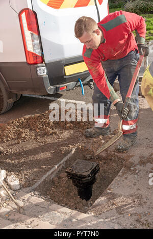 Installing a new water meter in the road. UK. Man filling a hole with the new meter having been installed Stock Photo