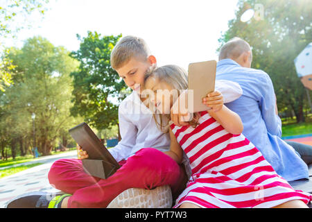 Group of busy kids looking at their phones texting sms and playing sitting outside Stock Photo