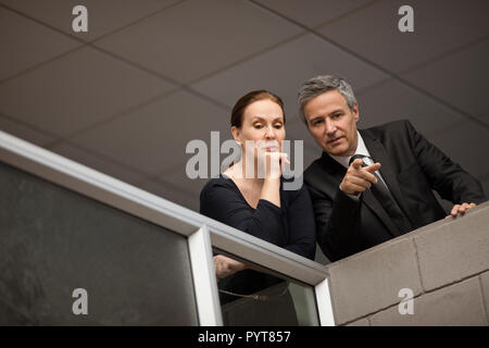 Male and female architects discussing an architectural feature. Stock Photo