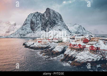 Famous tourist attraction Hamnoy fishing village on Lofoten Islands, Norway with red rorbu houses. With falling snow in winter on sunrise Stock Photo