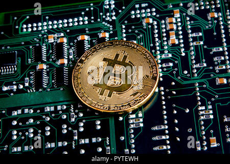 Bitcoin gold coin representing cryptocurrencies on a green & black computer circuit. Stock Photo