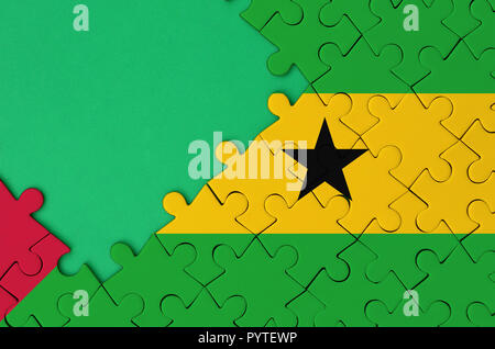 Sao Tome and Principe flag  is depicted on a completed jigsaw puzzle with free green copy space on the left side. Stock Photo