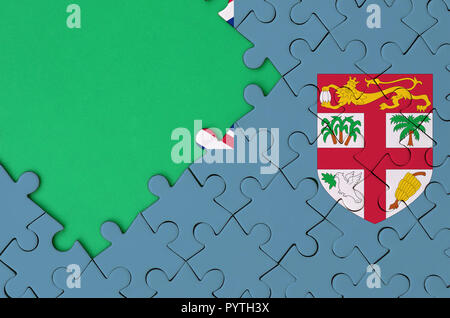 Fiji flag  is depicted on a completed jigsaw puzzle with free green copy space on the left side. Stock Photo