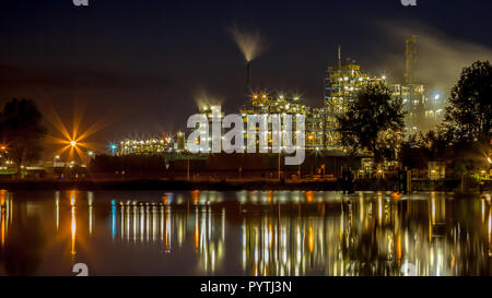 Night scene of detail of a heavy Chemical Industrial area with pipes and lights reflecting in the water Stock Photo