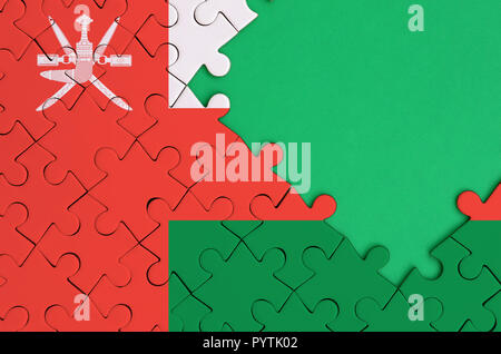 Oman flag  is depicted on a completed jigsaw puzzle with free green copy space on the right side. Stock Photo
