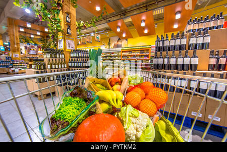 Grocery shop cart in supermarket filled up with fresh and healthy food products on the wine and alcohol section as concept for willpower and unhealthy Stock Photo