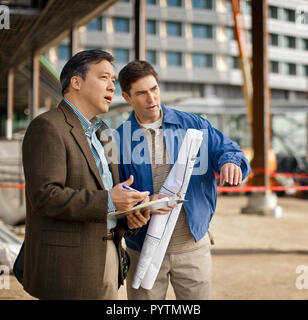 Business colleagues discussing plans at a construction site. Stock Photo