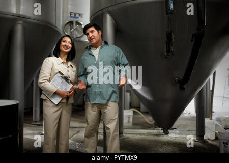 Two smiling colleagues discussing work in a warehouse. Stock Photo