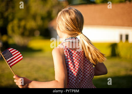 Young girl holding an American flag in her back yard. Stock Photo