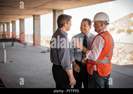 A construction manager and two executives talking on construction site. Stock Photo