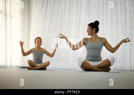 Smiling young girl and young woman meditating. Stock Photo