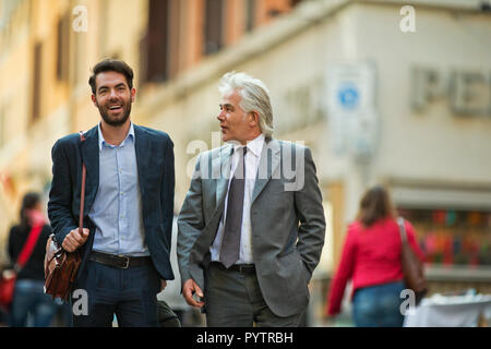 Mature businessman has a chance meeting with a young colleague while they are out in the city. Stock Photo