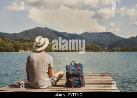 travel, summer holidays, tourist with backpack relaxing on wooden pier, vacation trip Stock Photo