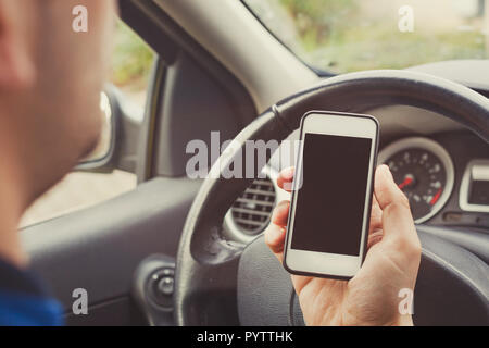 Man using smartphone in car, driver holding mobile phone with empty blank screen. Stock Photo