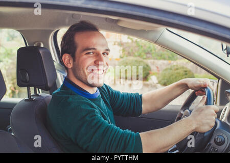 Portrait of happy driver in car. Smiling young man looking at camera who got his driving license. Stock Photo