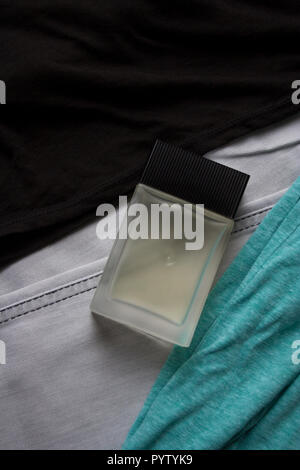Glass perfume bottle on black and mint tank tops and light grey jeans Stock Photo