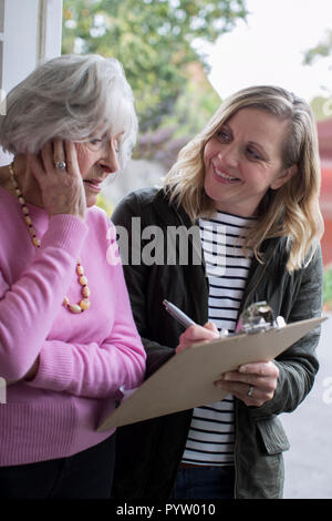 Female Sales Person Trying To Persuade Senior Woman To Purchase Goods Or Services Stock Photo