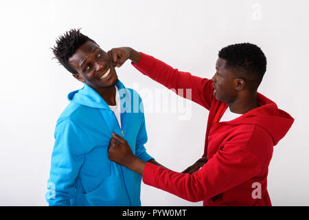 Studio shot of young black African man punching happy slim black