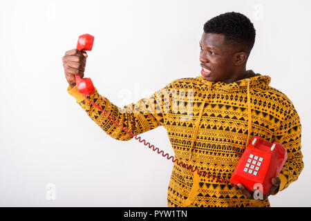 Studio shot of young angry black African man looking at old tele Stock Photo